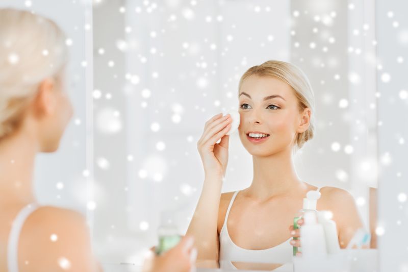 young woman with lotion washing face at bathroom